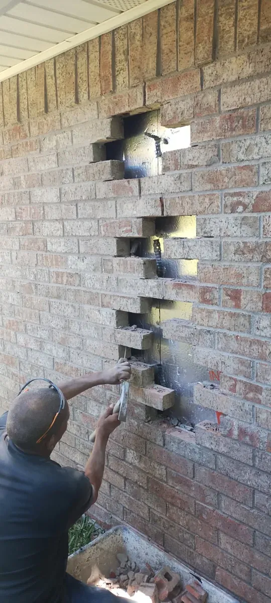 Damaged brick being removed from an exterior wall