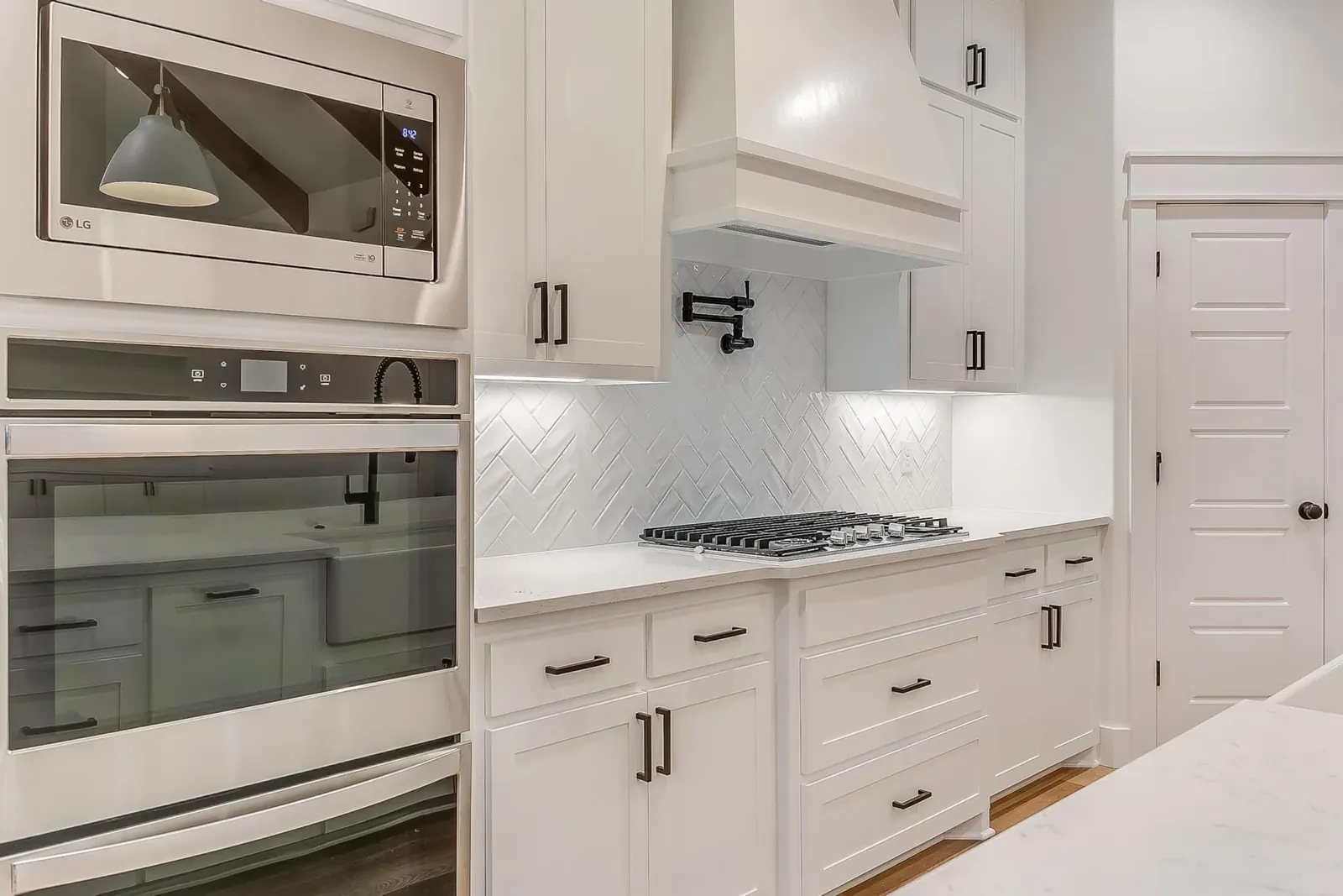 Remodeled white kitchen with double wall ovens and gas cooktop